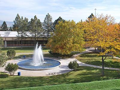 校园秋天的照片，包括喷泉、草坪和绿树和黄叶